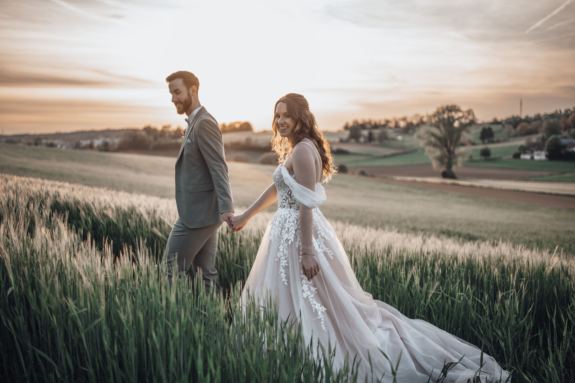 Bräutigam hält die Hand der Braut und läuft mit ihr über ein Feld – Hochzeitsfotograf Heidelberg beim romantischen Brautpaarshooting.