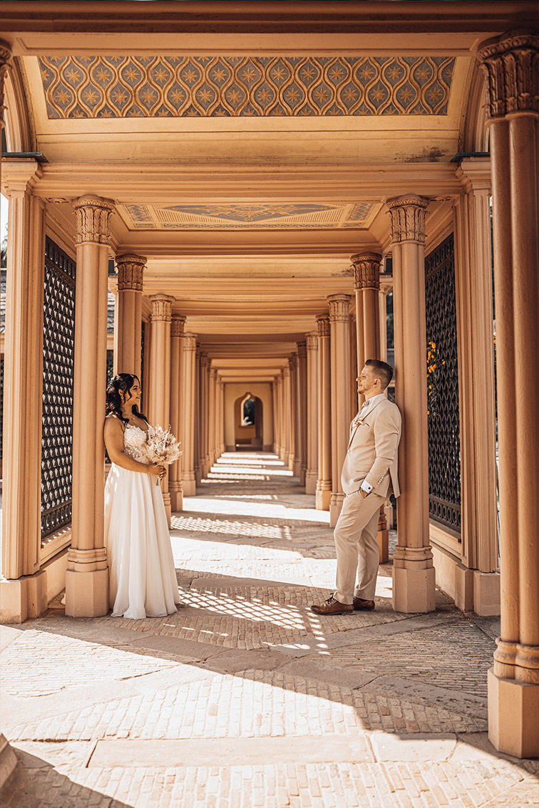 Braut steht in ihrem weißen Hochzeitskleid vor historischen Säulen